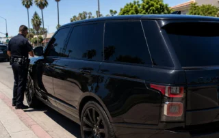 Police officer conducting a traffic stop on a vehicle with dark tinted windows in California